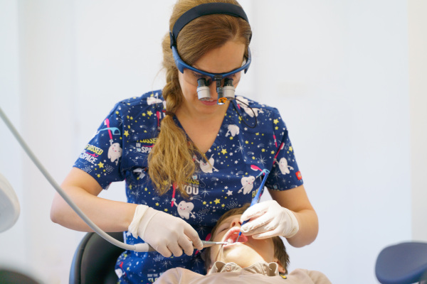 Young woman dentist doing doing preventive examination a little boy.