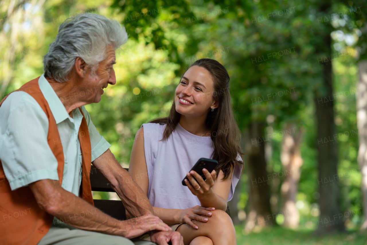 Caregiver helping senior man to shop online on a smartphone. The risk of online shopping scams targeting older people.