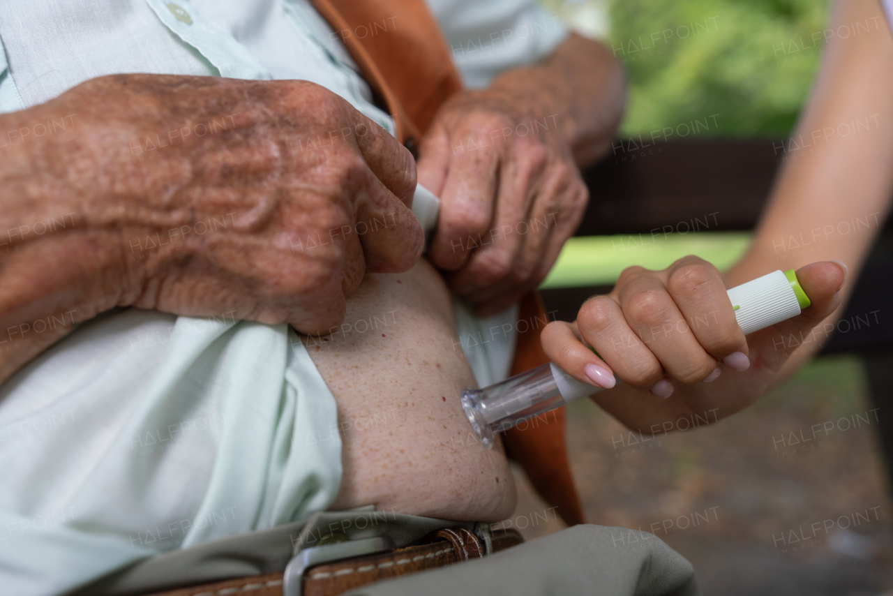 Nurse injecting insulin in belly of diabetic senior patient Close up of senior man with type 1 diabetes taking insuling with syringe needle in city park. Nurse teaching elderly man how to inject injection himself.