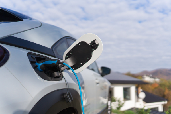 Charging electric car with own charger in house, sustainable transportation concept.