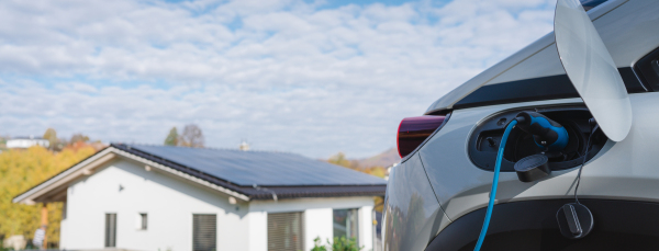 Charging electric car with own charger in house, sustainable transportation concept.