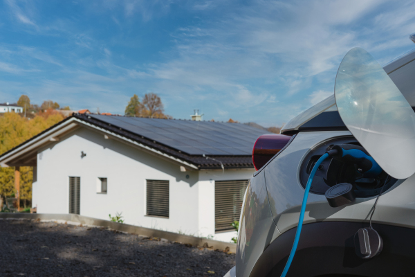 Charging electric car with own charger in house, sustainable transportation concept.