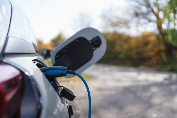 Charging electric car with own charger in house, sustainable transportation concept.