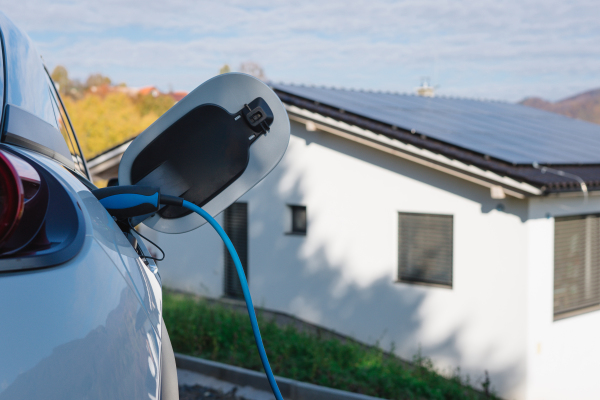 Charging electric car with own charger in house, sustainable transportation concept.