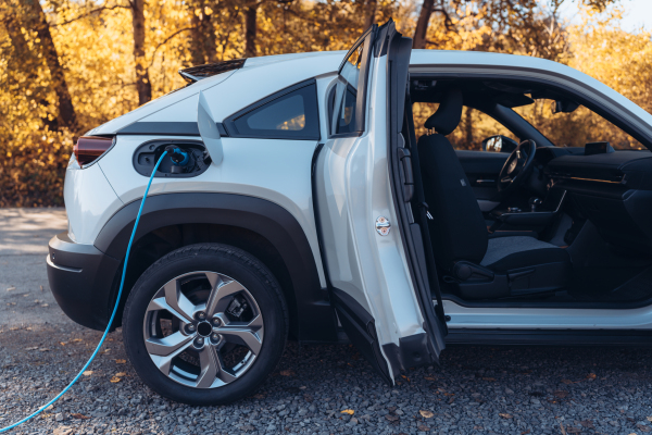 Charging electric car with own charger in house, sustainable transportation concept.