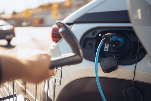 Close-up of charging electric car at supermarket parking.