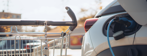 Close-up of charging electric car at supermarket parking.