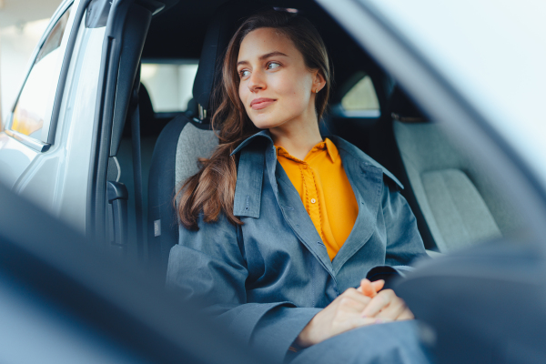 Excited young woman sitting in her car, waiting for somebody.