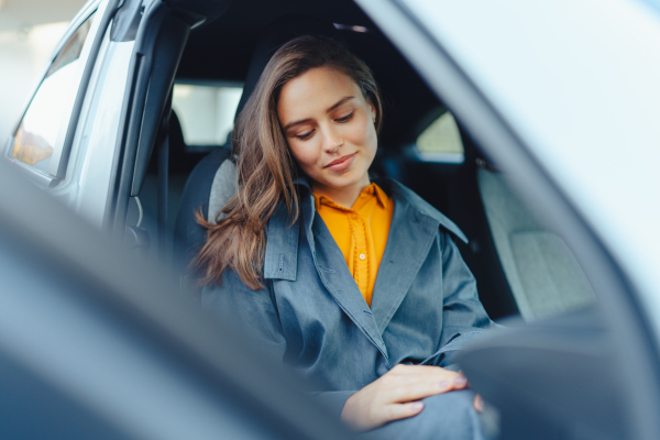 Excited young woman sitting in her car, waiting for somebody.