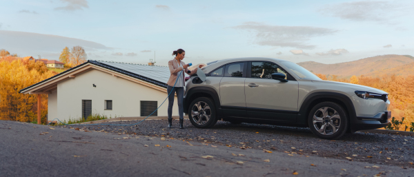 Young woman charging electric car in home, sustainable and economic transportation concept.