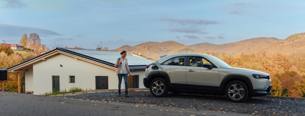 Young woman charging electric car in home, sustainable and economic transportation concept.