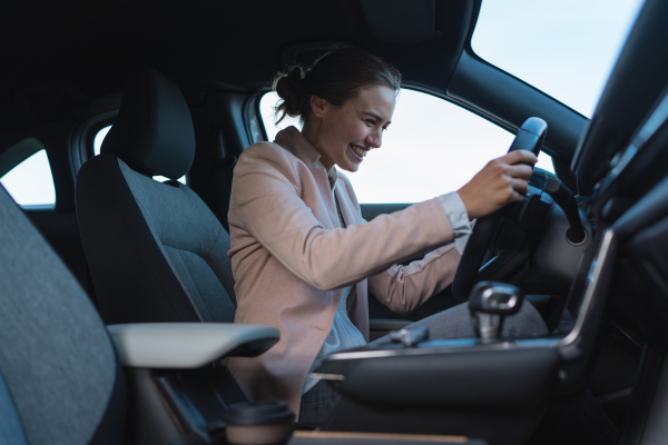 Excited young woman driving electric car.