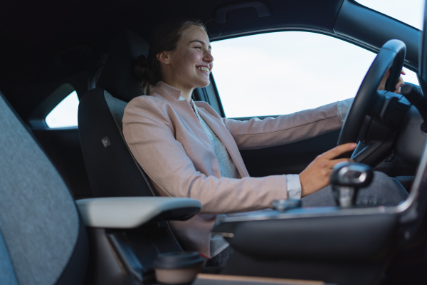 Excited young woman driving electric car.