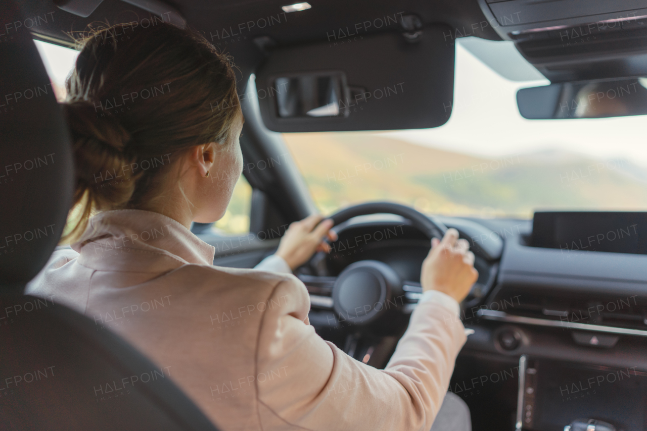 Rear view of young woman driving electric car.