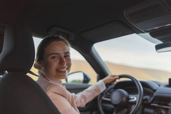 Rear view of young woman driving electric car.