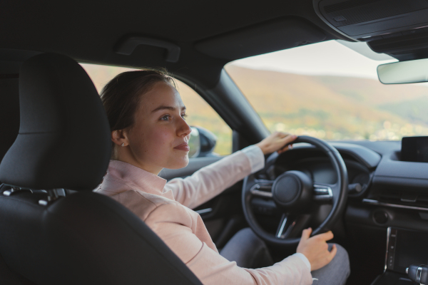 Excited young woman driving electric car.