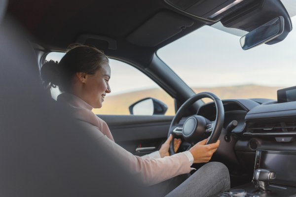 Excited young woman driving electric car.