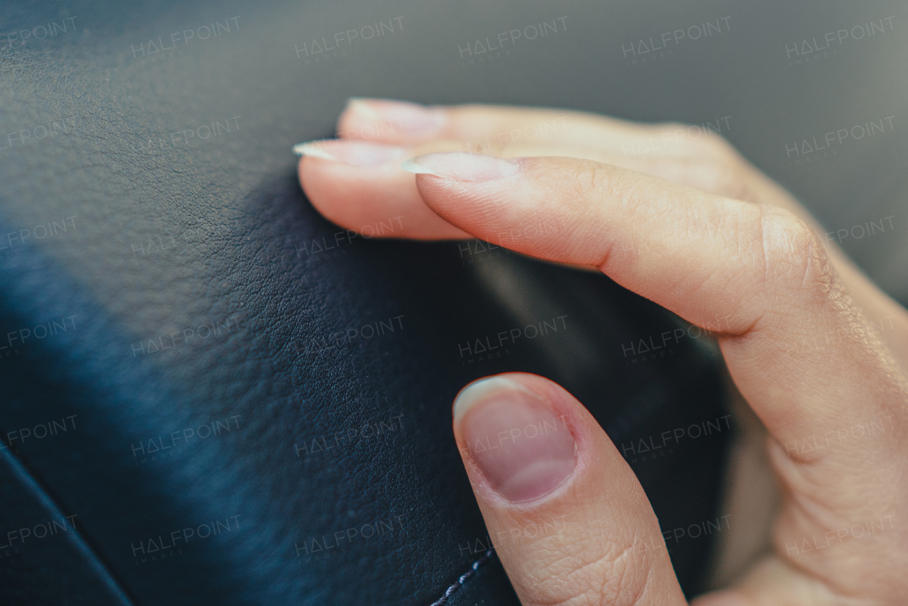 Close-up of young woman's hand touching a car interior.