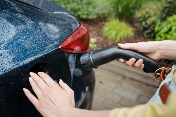 Close up of a woman holding electric charger for electric car. An electric vehicle charging station.