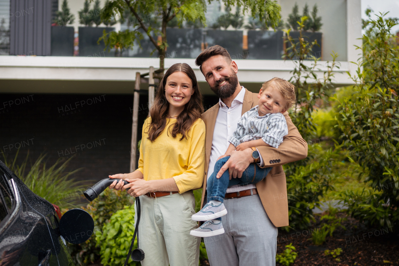 Happy young family with little son charging the electric car.