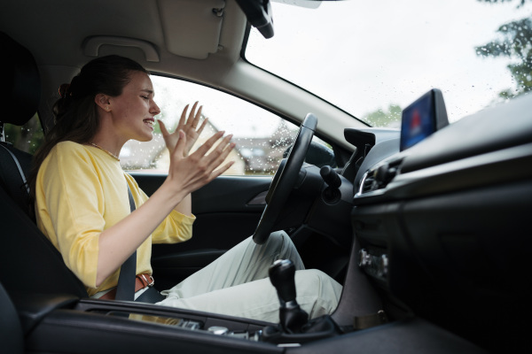 Angry woman sitting in electric car with drained battery. Electric vehicle runs out of battery, power unexpectedly.