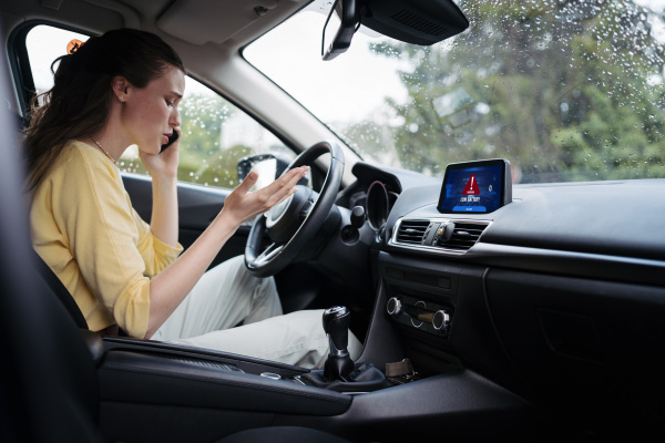 Young woman sitting in electric car with drained battery, making a phone call to the service center.