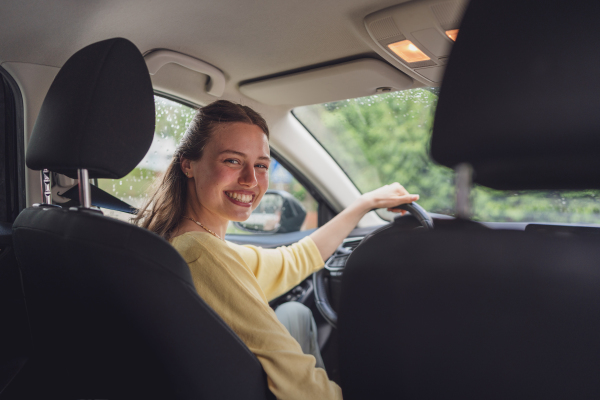 Portrait of young woman sitting in the driver's seat in car. Happy woman buying and driving her first own car.