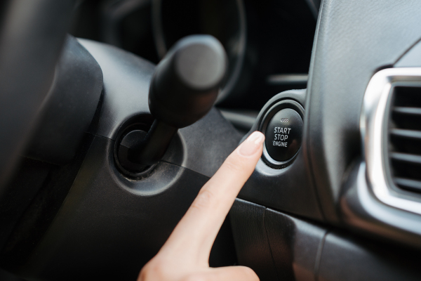 Close up of finger pressing engine start button until engine turns on. A keyless ignition system.