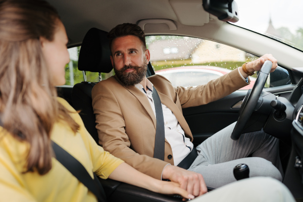 Portrait of young couple holding hands and sitting in their first new car. The newlyweds received a car as a wedding gift.