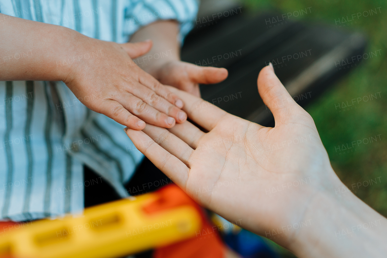 Mother and child are touching palms, expressing love. Close-up shot of child's and adult's touching hands. Concept of mother's Day and love.