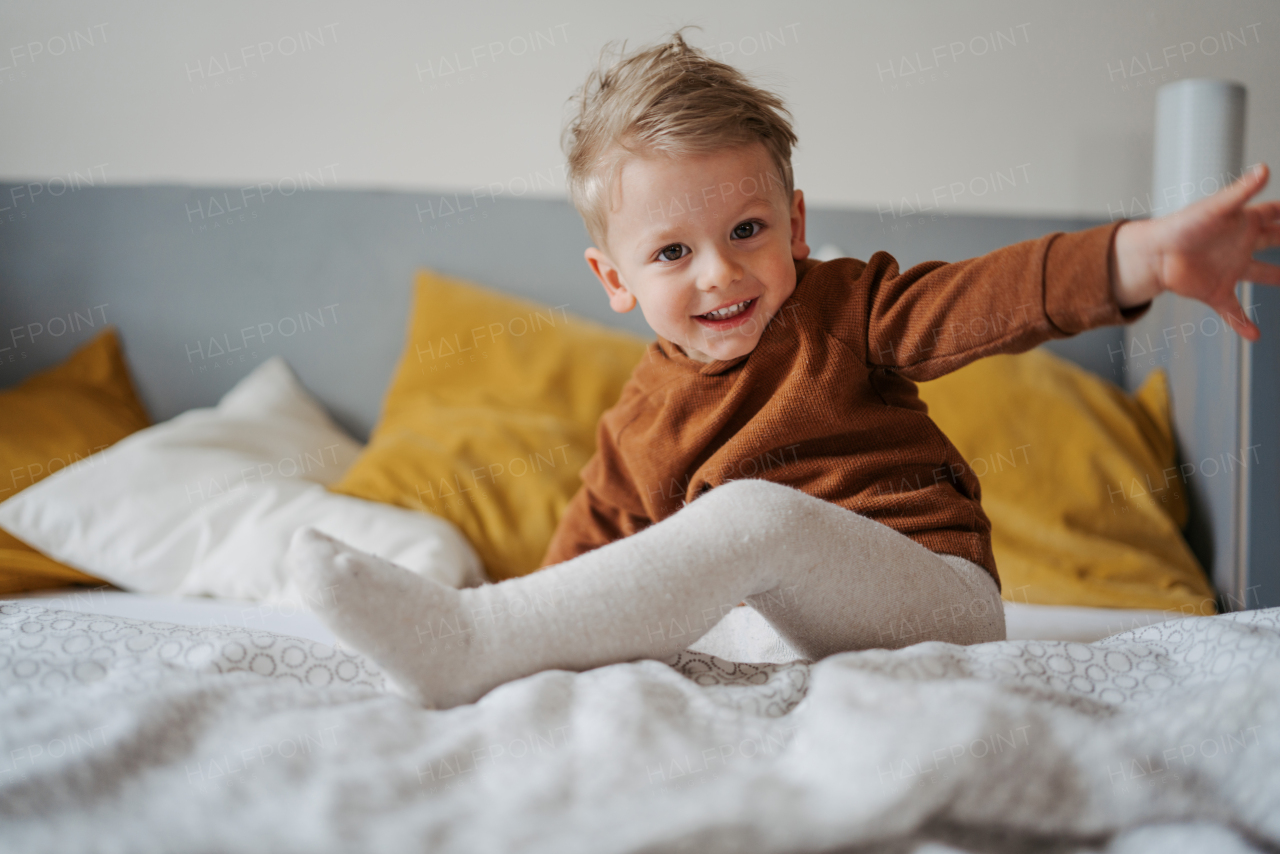 Portrait of little boy sitting on the bed.