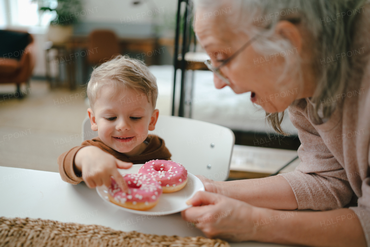 Little boy having sweet snack with his grandmother.