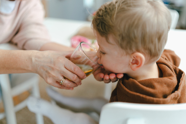 Grandmother giving glass of water to her little grandson.