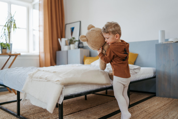 Little boy cuddling with bear toy in bedroom. Little boy going to sleep with toy.