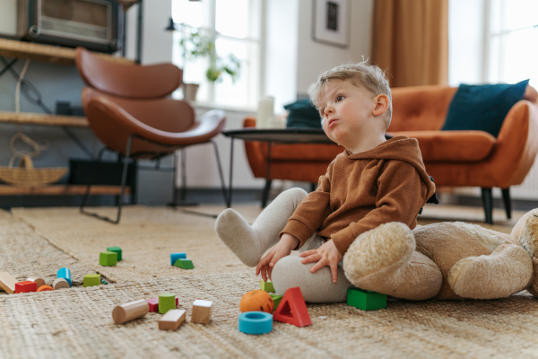 Little boy sitting on carpet and playing with the cubes.