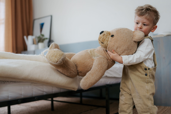 Little boy cuddling with bear toy in bedroom. Little boy going to sleep with toy.