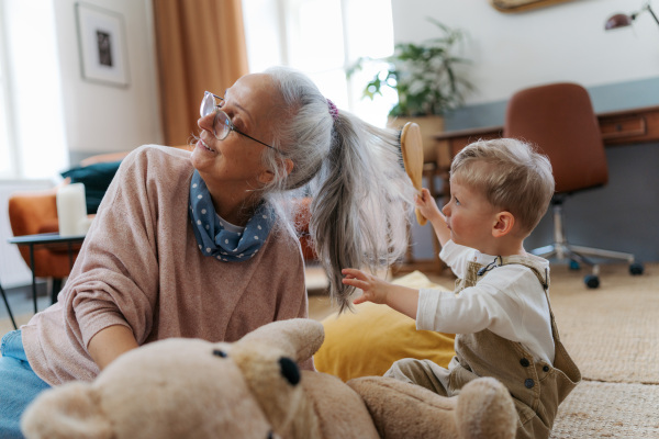 Little boy combing his grandomther with a hairbrush.