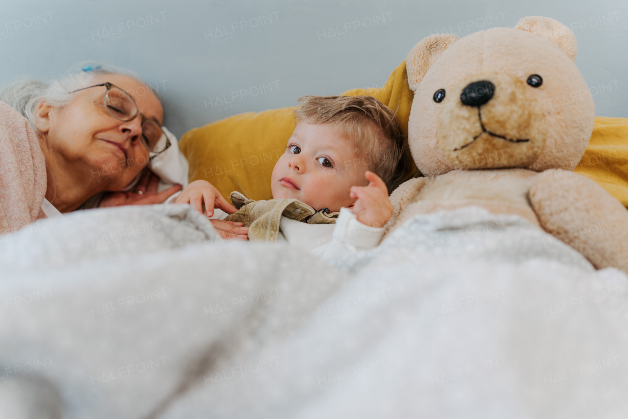 Grandmother lying with her grandson in a bed.