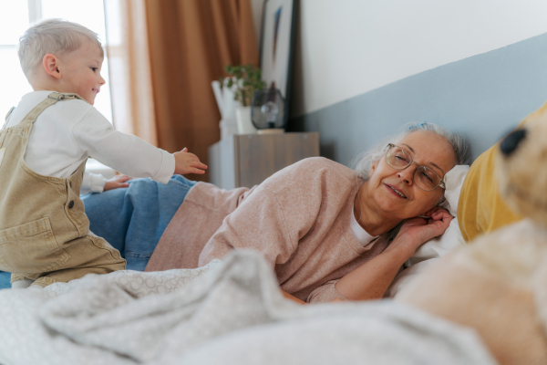 Grandmother lying with her grandson in a bed.