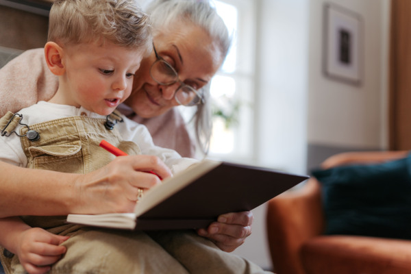 Grandmother drawing in notepad with her little grandson.