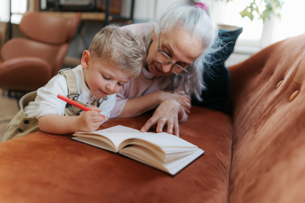 Grandmother drawing in notepad with her little grandson.