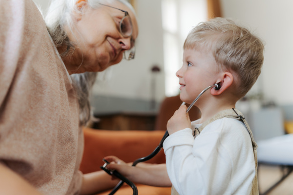 Little boy examining his grandmother, playing for a doctor.