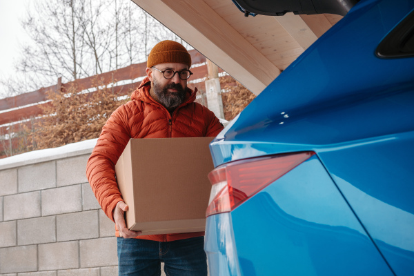 Man buying christmas gifts during winter, bringing box home. Mature man moving to the new house, packing into cardboard boxes.