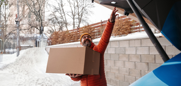 Man buying christmas gifts during winter, bringing box home. Mature man moving to the new house, packing into cardboard boxes.