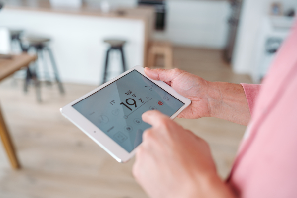 Man using smart thermostat, adjusting or lowering heating temperatures at his home. Concept of sustainable, efficient, and smart technology in home heating and thermostats.