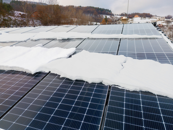 Roof solar panels with snow on top of them. Solar energy in the winter.