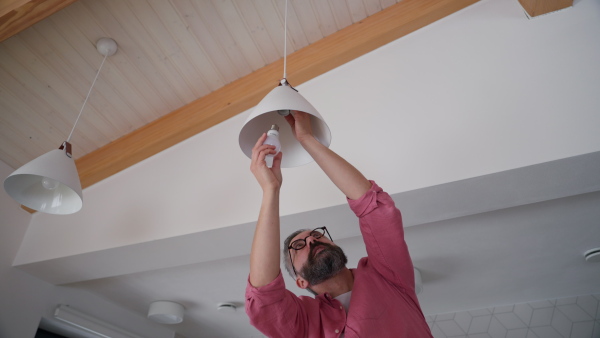 Man changing LED bulbs at home. Concept of energy efficiency, longevitiy and environmental impact of an electronic bulb.