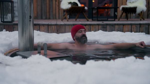 Mature man doing winterisation outside in small ponds next to his cabin.