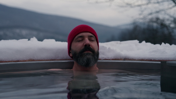 Mature man doing winterisation outside in small ponds next to his cabin.