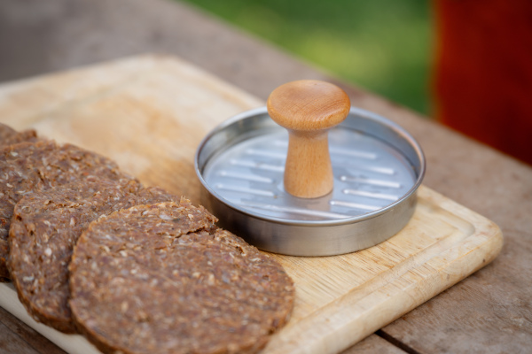 Close up of preparing meat for hamburgers. Using burger patty press to shape groud meat